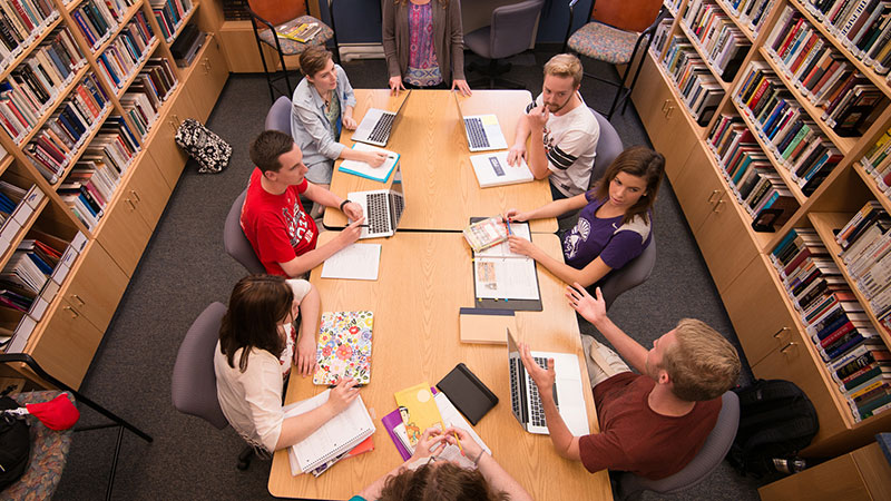 Image of students sitting around a desk at the library
