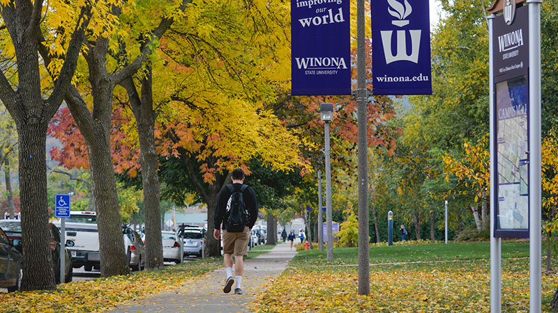 Outdoor image of a student walking on a sidewalk through WSU campus